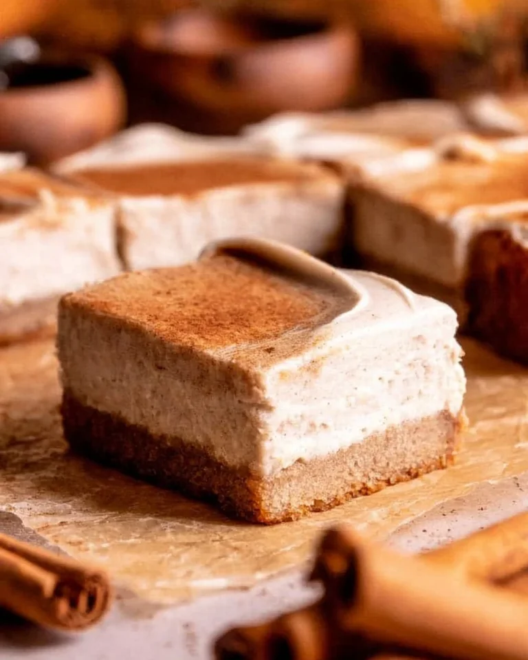 Chai cheesecake bars topped with a sprinkle of cinnamon and cardamom